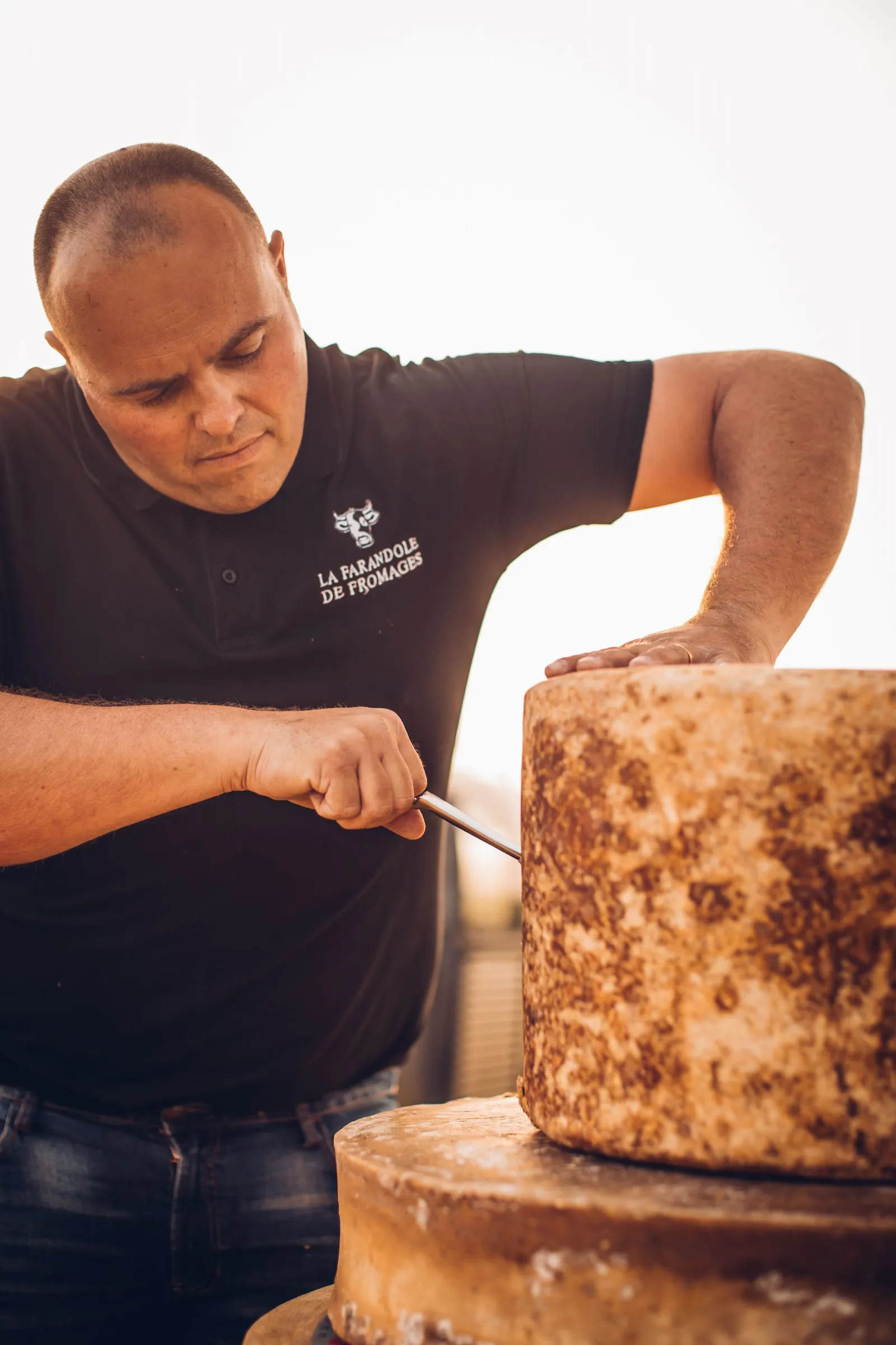 Freddy coupe une meule de fromage à la main